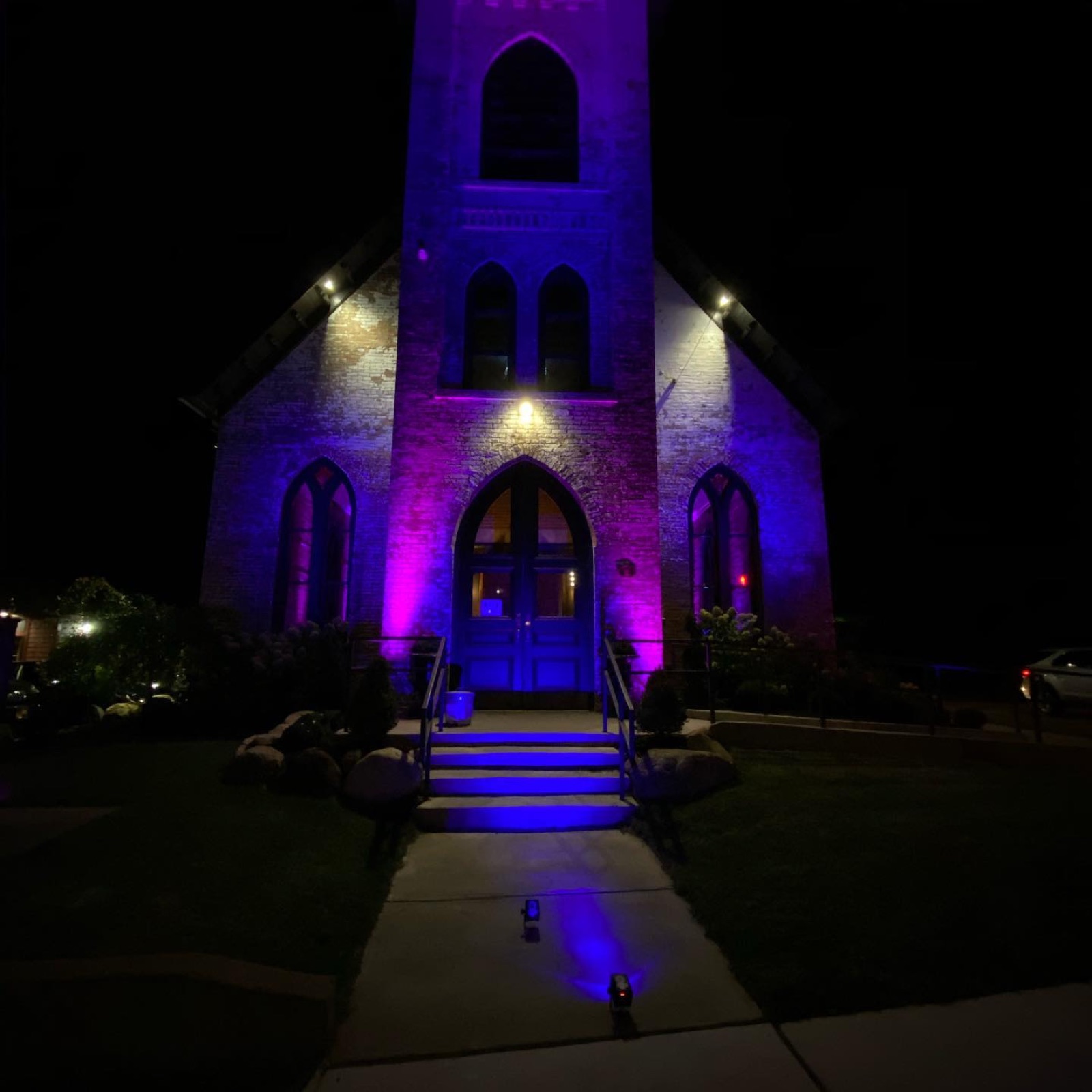 A stone church uplit purple at night